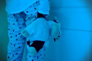 Niño en la cama con miedo a dormir, sobre fondo azul